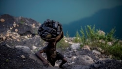 A man climbs a steep ridge with a basket of coal scavenged from a mine near Dhanbad, an eastern Indian city in Jharkhand state, Friday, Sept. 24, 2021.(AP Photo/Altaf Qadri)