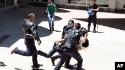 Turkish riot police try to protect a person from a group of people of unknown affiliation who were attacking a rally of pro-Kurdish Peoples' Democracy Party (HDP) in Erzurum, Turkey, June 4, 2015. 
