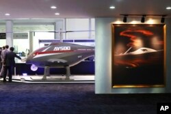 FILE - An unmanned helicopter drone AV500 and a painting of a drone are seen at a stand for the China National Aero-Technology Import & Export Corp., at a military drone expo in Abu Dhabi, United Arab Emirates, Feb. 25, 2018.