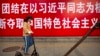 资料照：一名女子滑着踏板车路过北京街头的一条政治标语。（2017年10月12日）