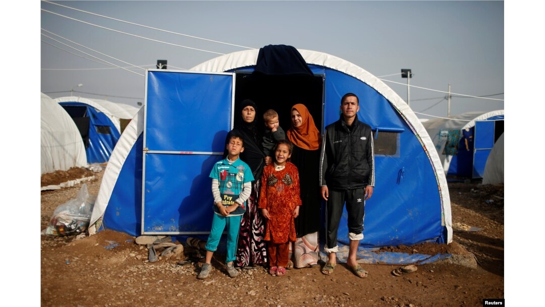 Displaced Iraqi Gorha Mahmoud (L), 40, poses for a photograph with family at Hammam al-Alil camp south of Mosul, Iraq, March 29, 2017.