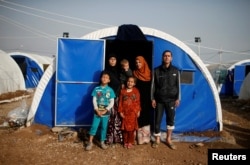Displaced Iraqi Gorha Mahmoud (L), 40, poses for a photograph with family at Hammam al-Alil camp south of Mosul, Iraq, March 29, 2017.