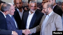 Senior Fatah official Azzam Al-Ahmed (L) shakes hands with senior Hamas leader Moussa Abu Marzouq after announcing a reconciliation agreement in Gaza City, April 23, 2014.