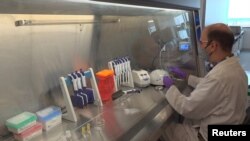 A technician inspects vials of coronavirus disease (COVID-19) vaccine candidate BNT162b2 at a Pfizer manufacturing site in manufacturing site in St. Louis, Missouri, U.S. in an undated photograph. (Pfizer/Handout via REUTERS)
