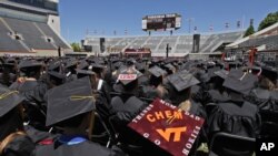 Los estudiantes siguen el discurso de la primera dama, Michelle Obama durante la ceremonia de graduación en Virginia Tech.