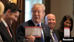 U.S. President Donald Trump holds sample tax forms as he promotes a newly unveiled Republican tax plan with House Republican leaders in the Cabinet Room of the White House in Washington, Nov. 2, 2017. 
