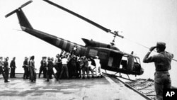 U.S. Navy personnel aboard the USS Blue Ridge push a helicopter into the sea off the coast of Vietnam in order to make room for more evacuation flights from Saigon on April 29, 1975. 