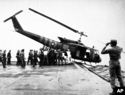 FILE - U.S. Navy personnel aboard the USS Blue Ridge push a helicopter into the sea off the coast of Vietnam in order to make room for more evacuation flights from Saigon, April 29, 1975.