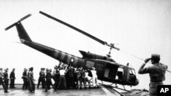 ທະຫານກອງທັບເຮືອ ສະຫະລັດ ຢູ່ເທິງກຳປັ່ນ USS Blue Ridge ຍູ້ເຮືອບິນເຮລີຄອບເຕີ ລົງທະເລ ນອກຊາຍຝັ່ງຂອງ ຫວຽດນາມ ເພື່ອຈັດບ່ອນຫວ່າງ ໃຫ້ຜູ້ຄົນ ທີ່ຖືກຍົກຍ້າຍ ອອກຈາກໄຊງ່ອນ. 29 ເມສາ, 1975. 