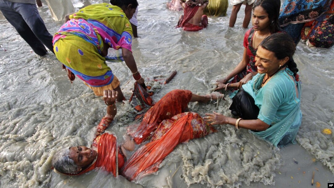 Seorang perempuan lansia ikut menceburkan diri dalam upacara di Sungai Ganga, India hari Senin (14/1).