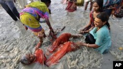 Seorang perempuan lansia ikut menceburkan diri dalam upacara di Sungai Ganga, India hari Senin (14/1).