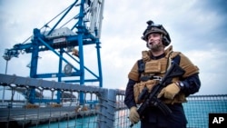 A security forces member stands guard aboard the Norwegian frigate Helge Ingstad, in Limassol, Cyprus, Dec. 28, 2013.