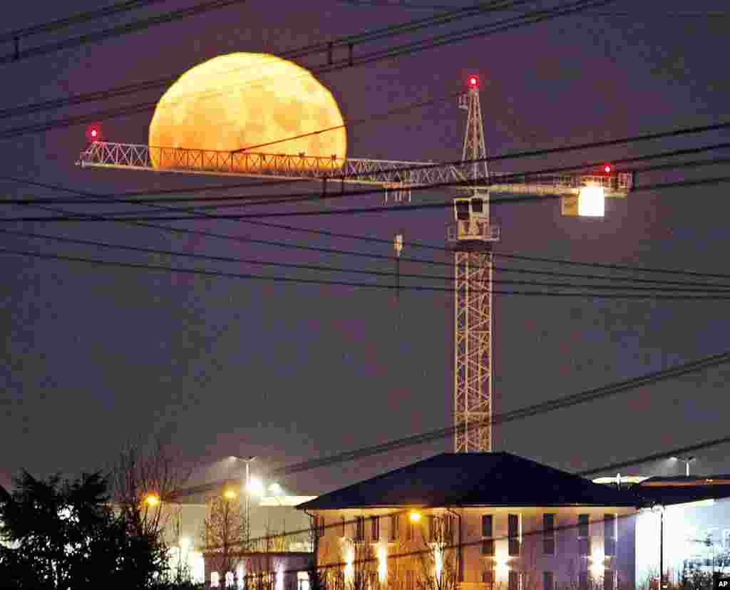 The rising full moon seems to sit on a crane in Frankfurt, Germany.