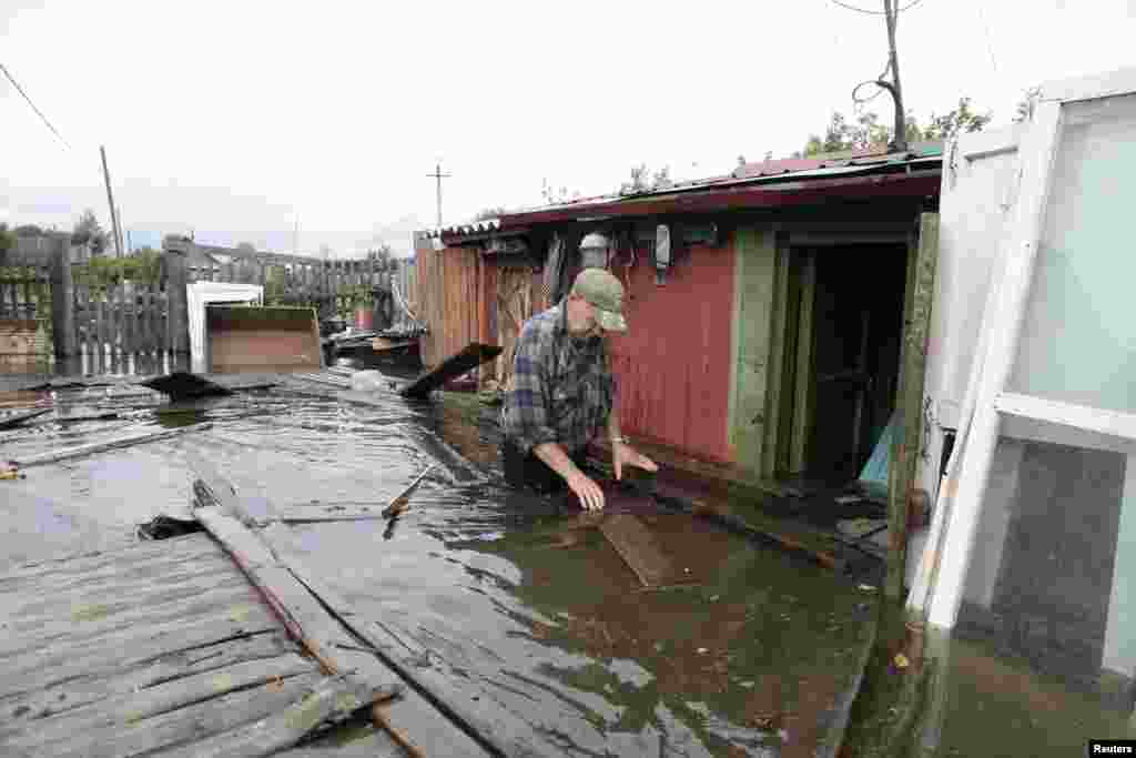 A man wades through a flooded garden in a village outside Komosomolsk-on-Amur in Russia&#39;s far eastern Khabarovsk region.
