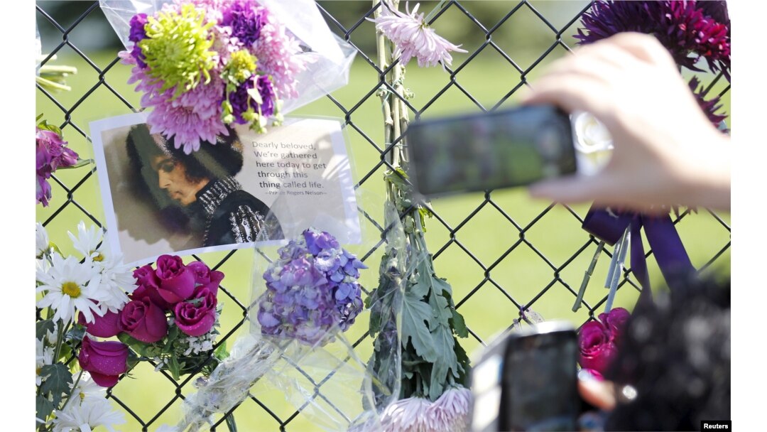 Fans take pictures of a makeshift memorial to musician Prince outside the fence of Paisley Park, his home and recording studio in Chanhassen, Minnesota, a day after his death on Apr 22, 2016. (Reuters)