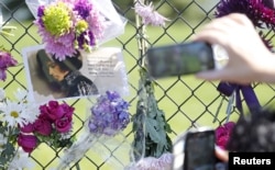 Fans take pictures of a makeshift memorial to musician Prince outside the fence of Paisley Park, his home and recording studio in Chanhassen, Minnesota, a day after his death on Apr 22, 2016. (Reuters)