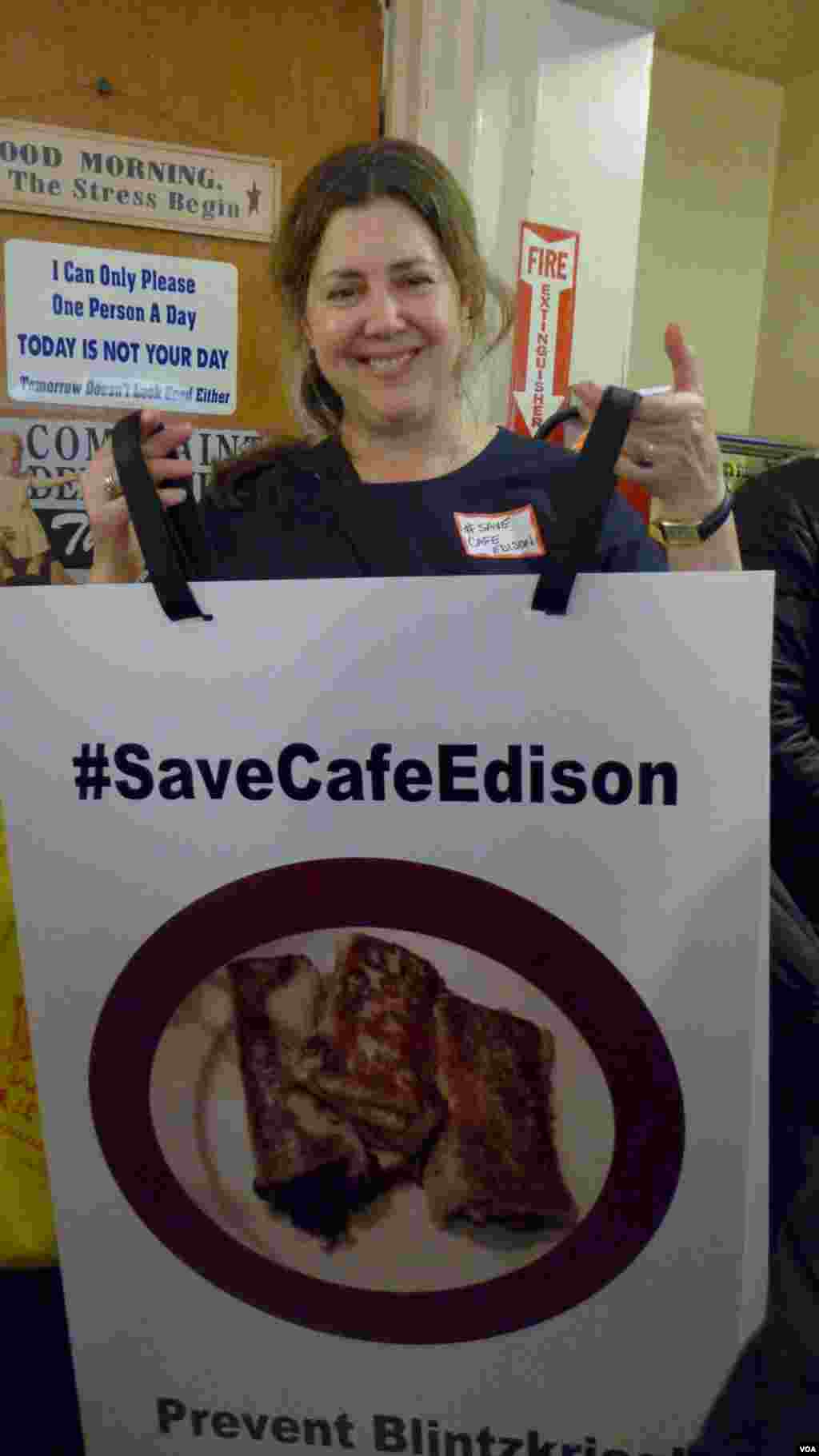 Liz Shelton’s protest sign features the Café’s famous blintzes, VOA / Jeff Lunden.