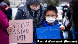 ایشیائی امریکی کمیونٹی کے احتجاج میں شریک ایک ماں اور بیٹا 'سٹاپ ایشئین ہیٹ'کا سائن اٹھائے ہوئے ہیں۔ فائل فوٹو رائٹرز