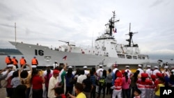 Warga melambaikan bendara Filipina saat menyambut kedatangan kapal BRP Ramon Alcaraz di Teluk Subic (6/8).