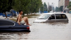 一名男子坐在暴雨後鄭州街頭漂浮的汽車上。 （2021年7月22日）