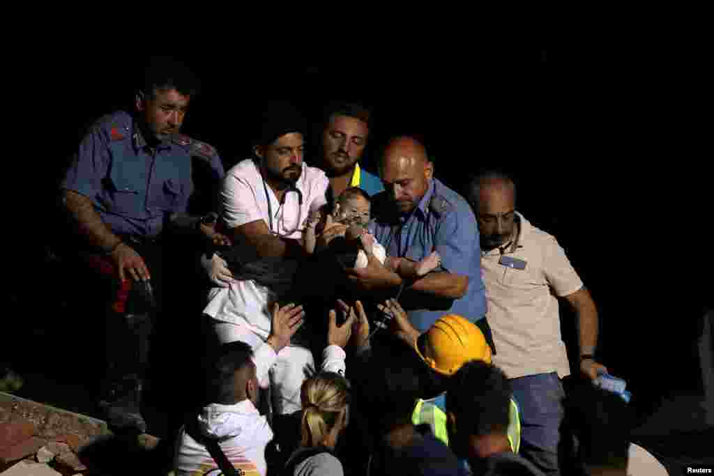 이탈리아 경찰과 의료진이 이스키아섬 지진 현장에서 유아를 구조하고 있다. 21일(현지시간) 발생한 규모 4.0 지진으로 최소한 2명이 숨지고 42명이 다친 한편, 이재민 2천600여명이 발생했다. &nbsp;