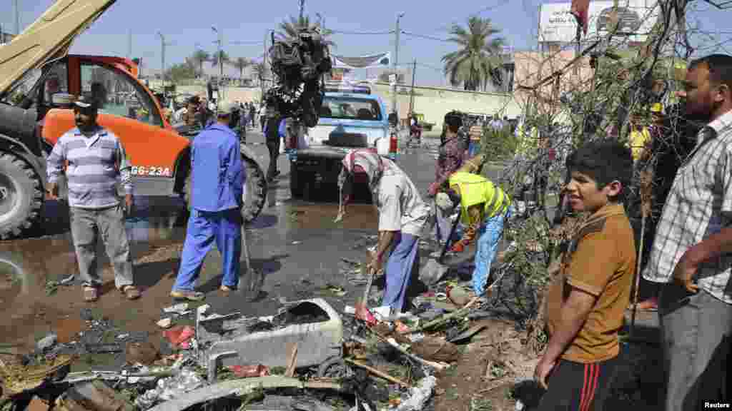 Street cleaners remove debris after a car bomb exploded in Diwaniya province, south of Baghdad, April 29, 2013.