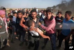 Palestinian protesters carry a wounded man who was shot by Israeli troops during a protest near the Gaza Strip border with Israel, in eastern Gaza City, March 31, 2018.