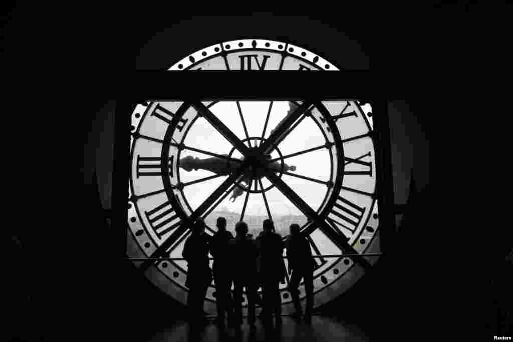 Visitors at the Musee d&#39;Orsay are seen in silhouette as they look on from a giant clock face at the former Orsay railway station, in Paris, France, July 28, 2015.