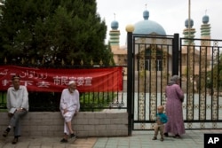 In this photo taken Thursday, July 17, 2014, Uighur residents gather outside a mosque in the city of Aksu in western China's Xinjiang Uighur Autonomous Region..