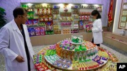 In this Oct. 22, 2018, photo, Kwon Yong Chol, left, the chief engineer at the Songdowon General Foodstuffs Factory, shows samples of products at his facility in Wonsan, North Korea. 
