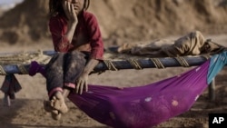 Pakistani Naginah Sadiq, 5, who works in a brick factory, rests on a bed next to her sister Shahzadi, 8 months, on World Day Against Child Labor, on the outskirts of Islamabad, Pakistan, June 12, 2012.
