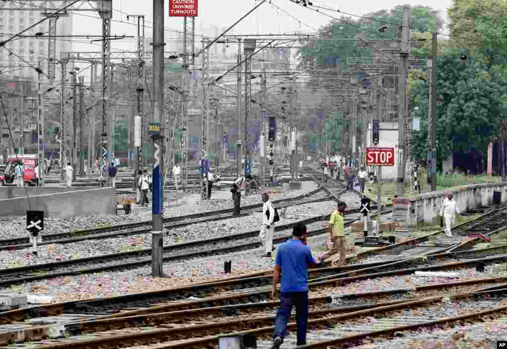 Commuters walk on empty railway tracks at the New Delhi railway station following a power outage in New Delhi, India, Tuesday, July 31, 2012.