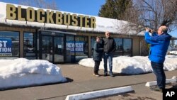 Debby Saltzman, of Bend, Ore., poses for a photo on Monday, March 11, 2019, in front of the last Blockbuster store on the planet with her twin brother, Michael Trovato. (AP Photo/Gillian Flaccus)