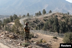 FILE - A soldier stands guard along the border fence at the Angoor Adda outpost on the border with Afghanistan in South Waziristan, Pakistan, Oct. 18, 2017.