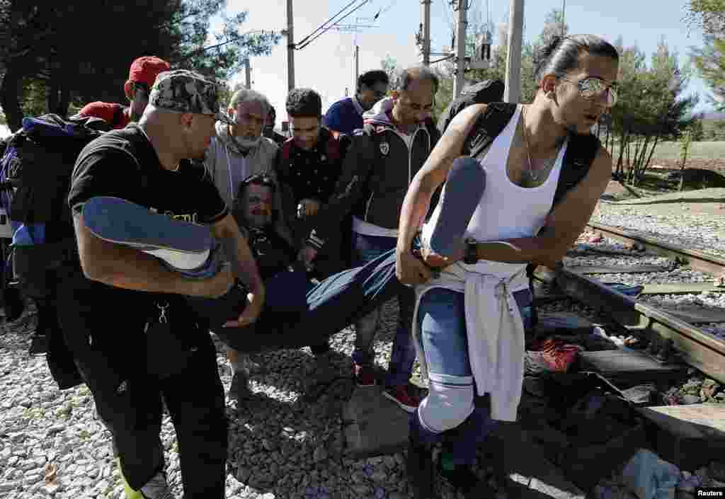 Syrian refugees carry a man on their way to cross the border from Greece into Macedonia on Saturday. Macedonia is considering building a border like Hungary&#39;s to stem the influx of migrants from the south.