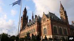 FILE - A United Nations flag flutters in the wind next to the International Court of Justice in the Hague, the Netherlands, Aug. 27, 2018. 