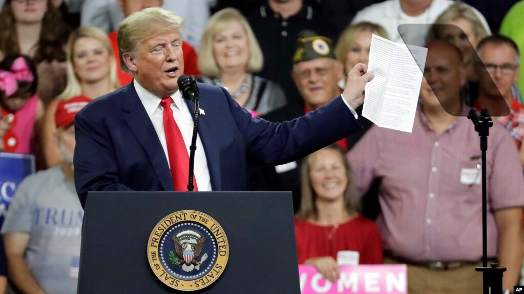 El presidente de EE.UU., Donald Trump, sostiene una lista de logros de su administración mientras habla en un acto de campaña en Johnson City, Tennessee, el lunes, 1 de octubre de 2018.