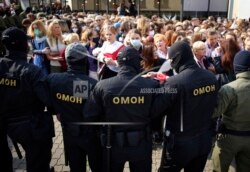 Women react, standing in front of police line during an opposition rally to protest the official presidential election results in Minsk, Belarus, Saturday, Sept. 12, 2020.