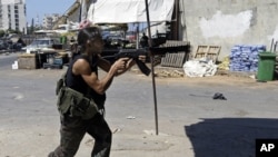 A Sunni gunman fires his AK-47 machine gun during clashes that erupted between pro and anti-Syrian regime gunmen in the northern port city of Tripoli, Lebanon, August 24, 2012.