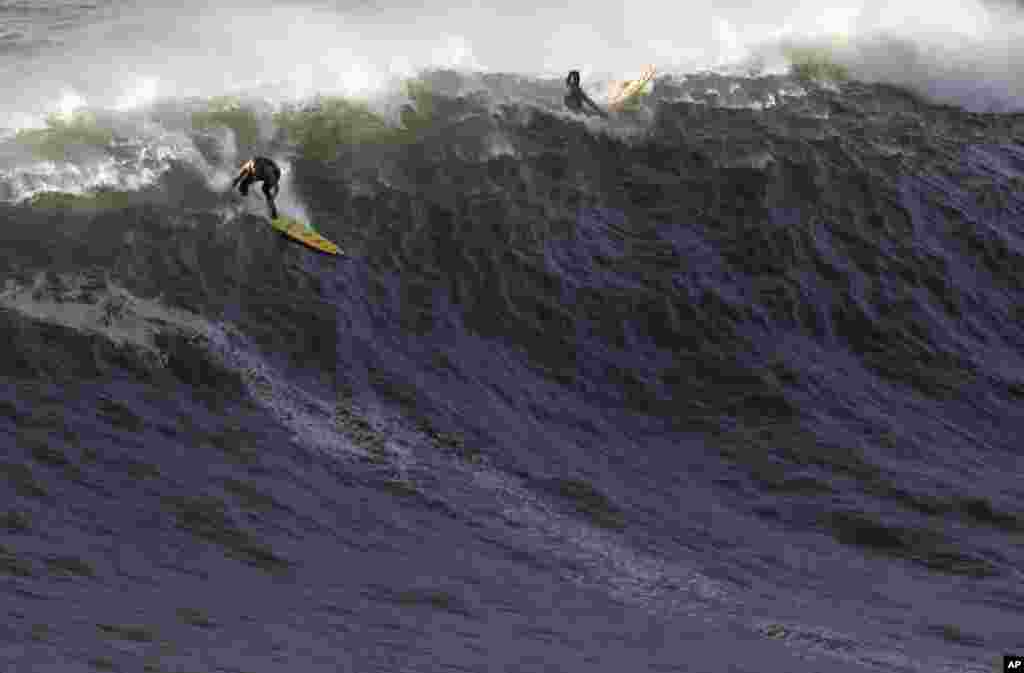 US surfer Garrett McNamara, left, makes a take off on a wave at Praia do Norte beach in Nazare, Portugal, Jan. 29, 2013.