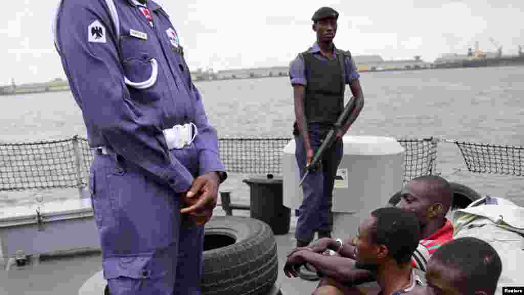 Naval police stand guard as suspected pirates are paraded aboard a naval ship after their arrest by the Nigerian Navy at a defence jetty in Lagos, August 20, 2013.