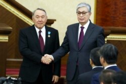 Kazakhstan's President Kassym-Jomart Tokayev, right, and outgoing Kazakh President Nursultan Nazarbayev shake hands after Tokayev's inauguration in Astana, Kazakhstan, March 20, 2019.