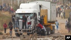 FILE: Rioters cling to the front of a lorry as they clash with Zimbabwean police in Harare, Monday, July, 4, 2016. (AP Photo/Tsvangirayi Mukwazhi)