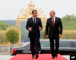 FILE - President Emmanuel Macron, left, and his Russian counterpart Vladimir Putin walk as they meet for talks at the Palace of Versailles, outside Paris, May 29, 2017.