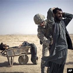 A US Army soldier searches an associate of a suspected Taliban IED placer, seen in a wheelbarrow, who was killed in a coalition missile strike in Zhari district, Kandahar province (File)
