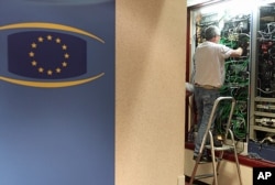 Communication technicians work at a phone and internet cable closet, at the European Council building in Brussels, July 1, 2013.