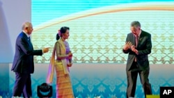 Singapore's Prime Minister Lee Hsien Loong, right gestures to Myanmar's Foreign Minister Aung San Suu Kyi, to move in closer for the group hand shake as Malaysia's Prime Minister Najib Razak, left, watches during the opening ceremony of the 28th and 29th ASEAN summits at National Convention Center in Vientiane, Laos, Tuesday, Sept. 6, 2016. 