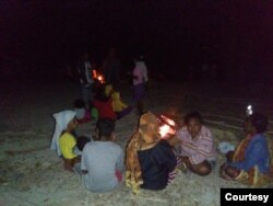 Warga komunitas adat Besipae, Rabu (19/8) duduk diatas tanah dengan penerangan api unggun sambil memeluk anak mereka yang tertidur. (Foto: Martheda Esterlina Selan)