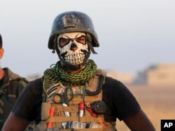 A member of Iraq's elite counterterrorism forces dons a mask for the advance on Mosul, Iraq, Oct. 20, 2016.
