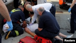 FILE - Paramedics and firefighters treat a man who was found unresponsive on a sidewalk after overdosing on opioids in Everett, Massachusetts, August 23, 2017.
